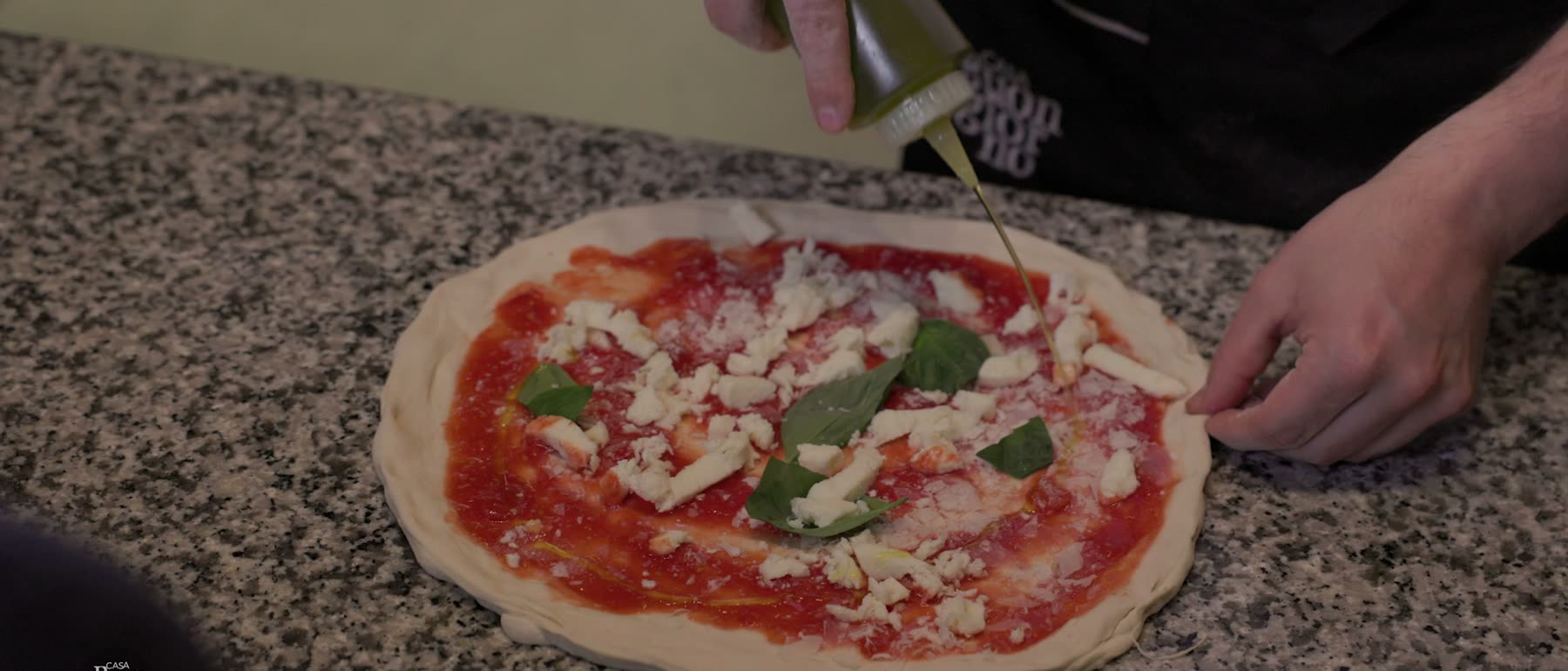 Pizza som tillagas för hand på en stenbänk